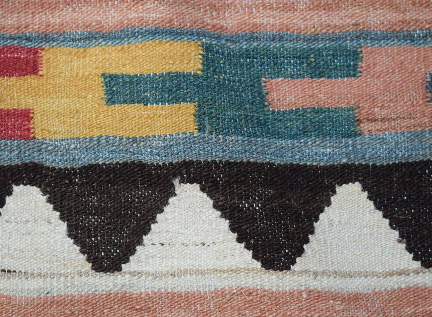 A close-up of a handmade Afghan Maimana kilim featuring geometric patterns in wool.