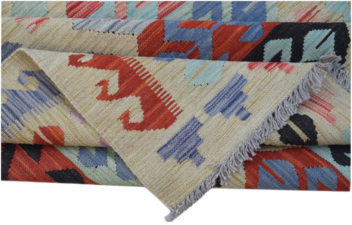 A handwoven Afghan Maimana kilim rug featuring geometric patterns in red, blue, and cream wool.