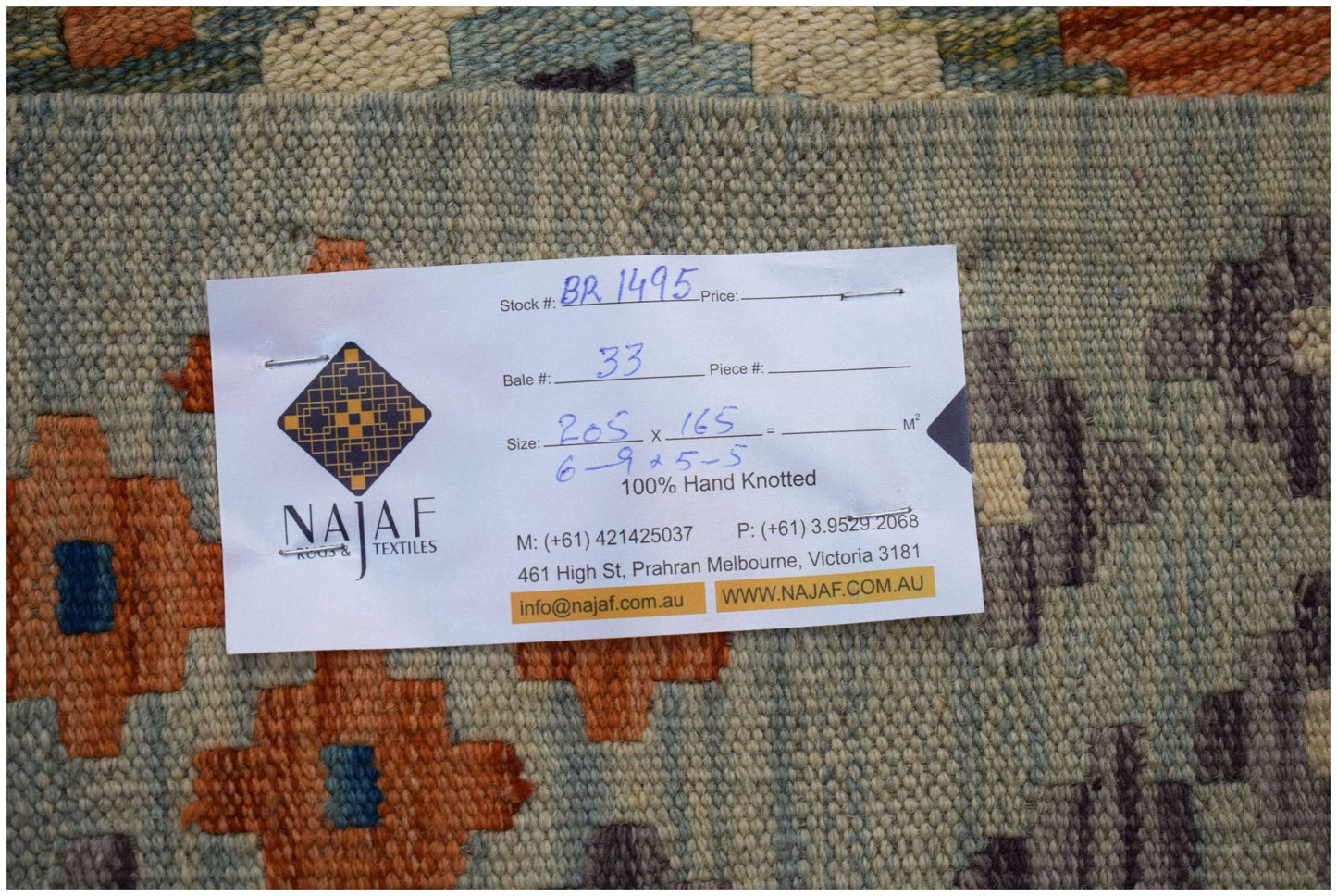 An Afghan Maimana Kilim rug featuring a geometric pattern in orange, blue, and grey tones.
