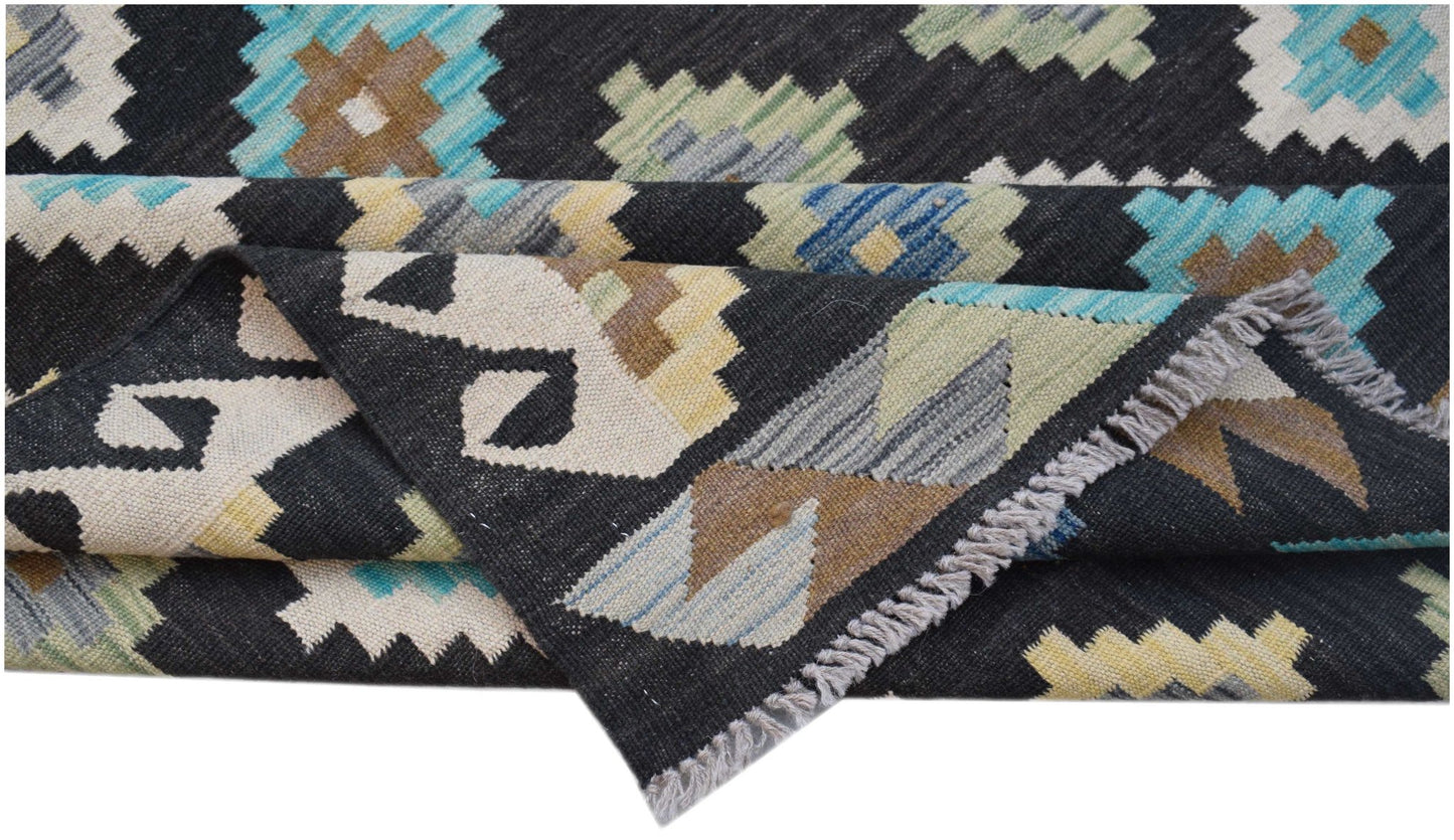 Handwoven Afghan Maimana kilim rug featuring a black background with colorful geometric patterns.