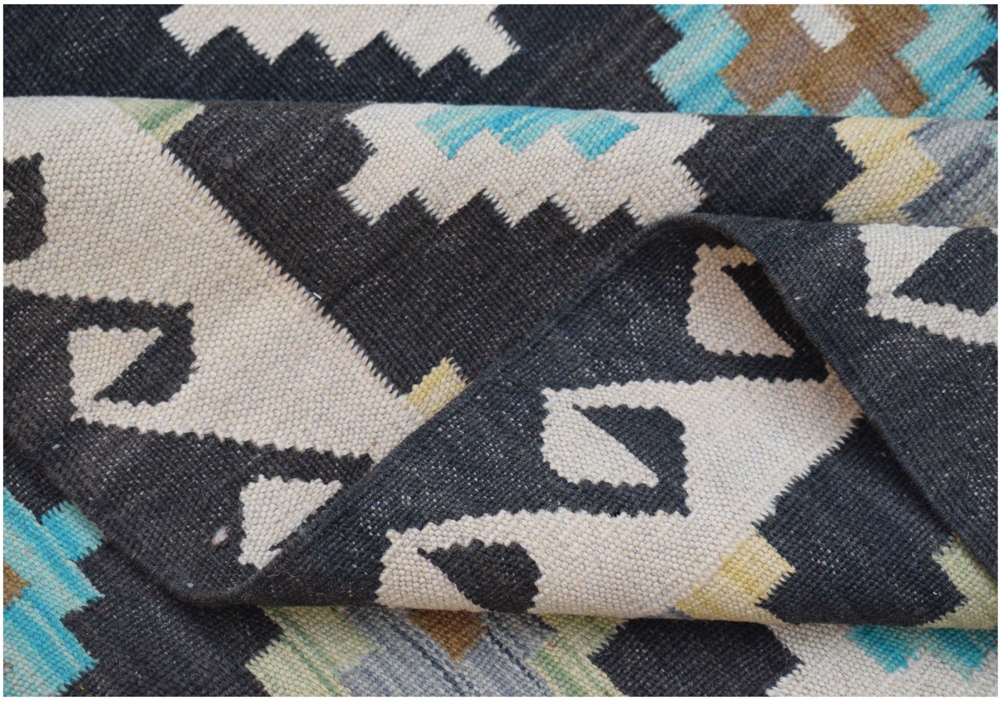 A handmade Afghan Maimana kilim rug featuring a geometric pattern in black, white, and blue tones.