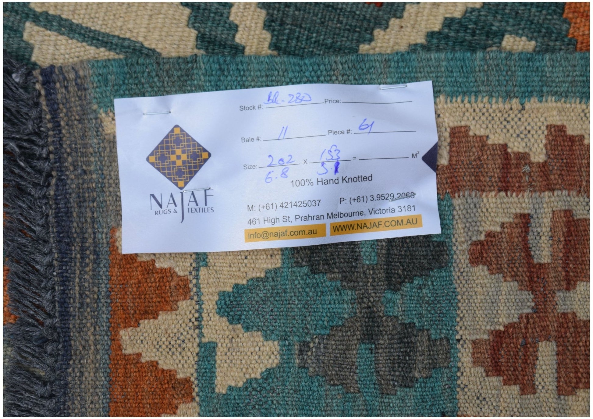 A handwoven Afghan Maimana kilim featuring a geometric pattern in teal, orange, and cream wool.