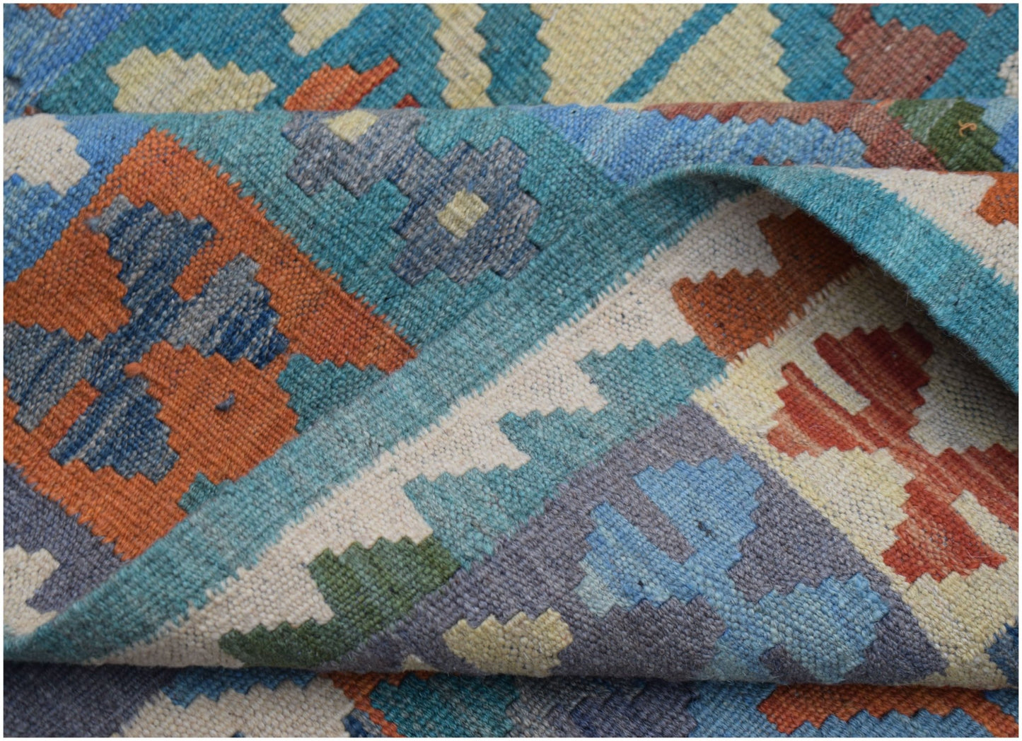 A handwoven Afghan Maimana kilim rug featuring a geometric pattern in blue, orange, and cream.