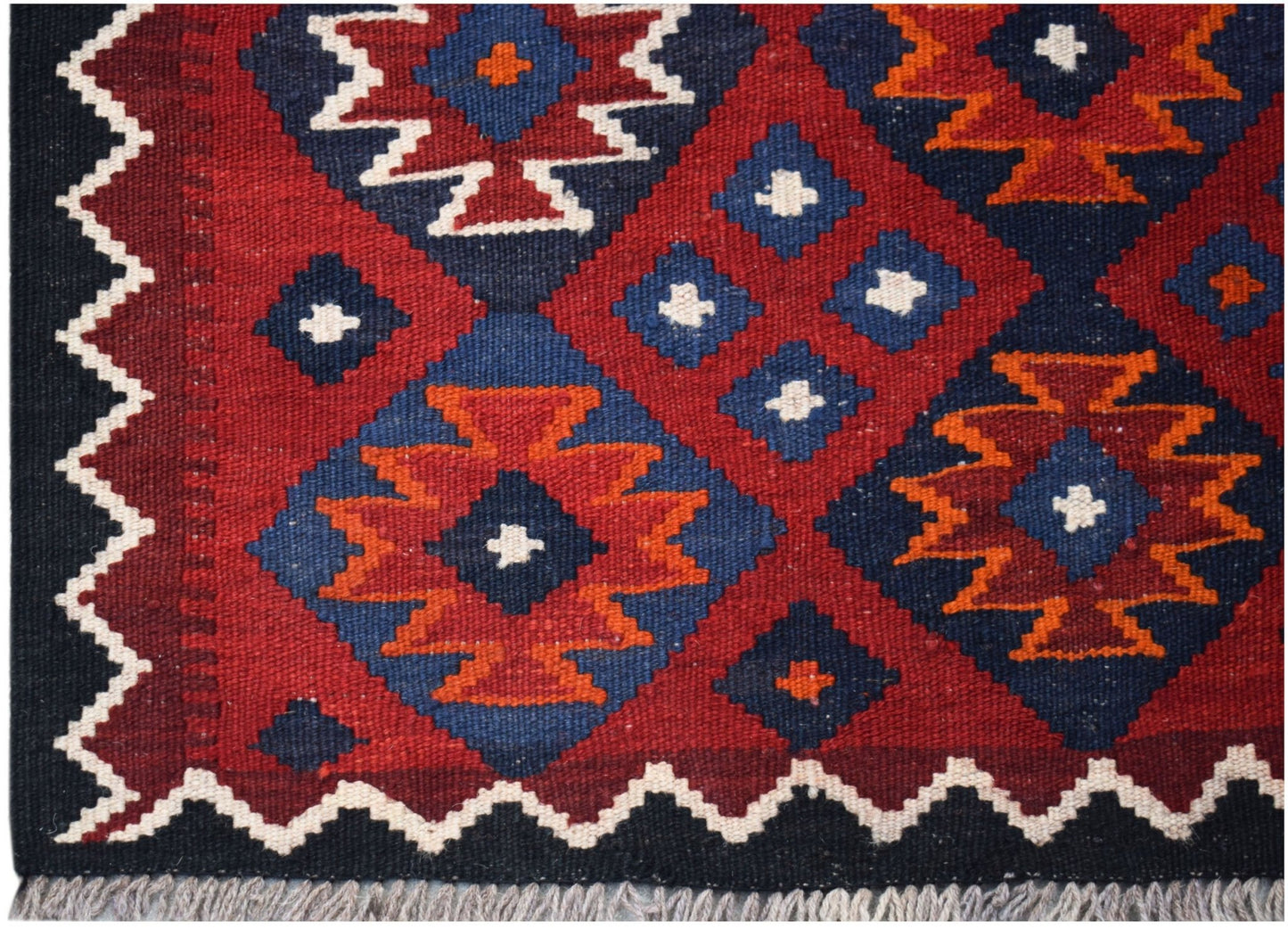 Handwoven Afghan Maimana kilim featuring a geometric pattern in red, blue, and orange wool.