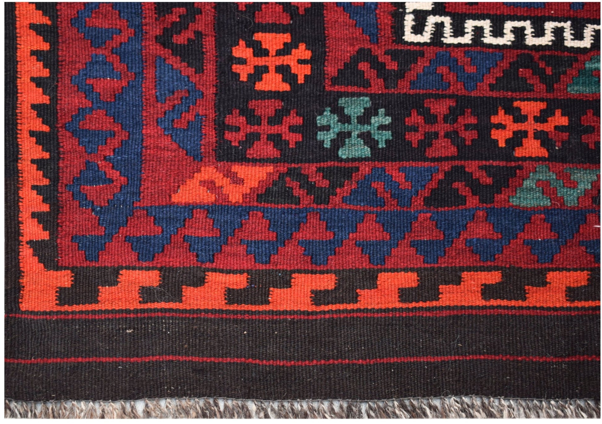 A handwoven Afghan Maimana kilim featuring geometric patterns in red, blue, and black wool.