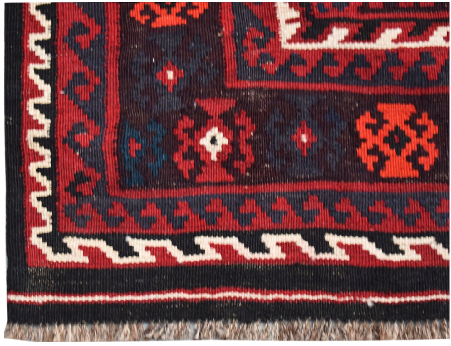 A handmade Afghan Maimana kilim featuring geometric patterns in red, black, and white wool.