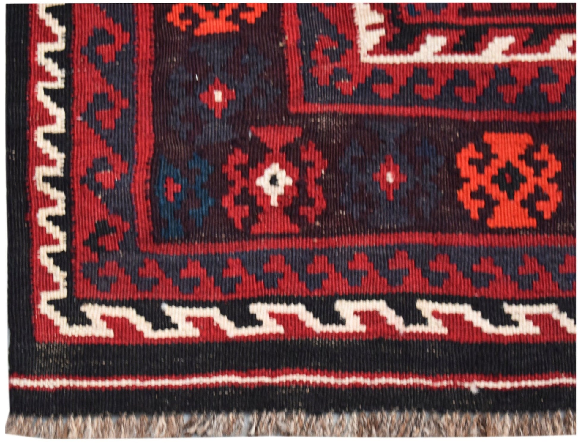 A handmade Afghan Maimana kilim featuring geometric patterns in red, black, and white wool.