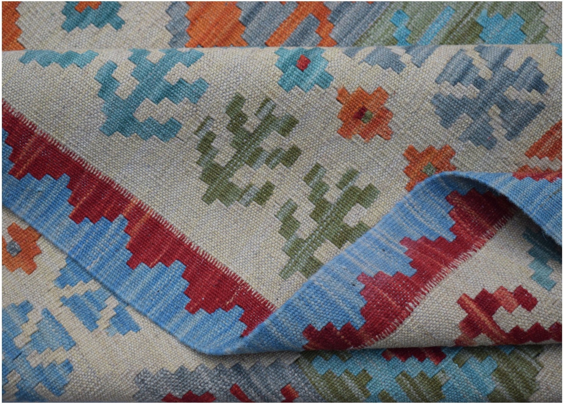 A handwoven Afghan Maimana kilim featuring a geometric pattern in blue, red, orange, and green.
