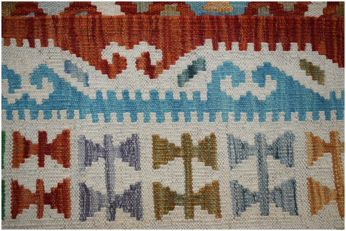 A close-up of a handmade Afghan Maimana kilim featuring geometric patterns in vibrant colors.