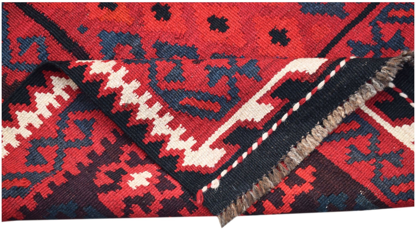 A handwoven Afghan Maimana kilim featuring a geometric pattern in red, black, and cream wool.