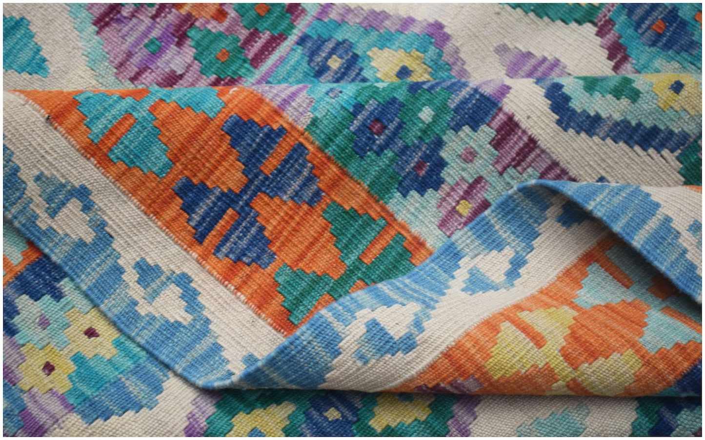 A handwoven Afghan Maimana kilim featuring a vibrant geometric pattern in wool.