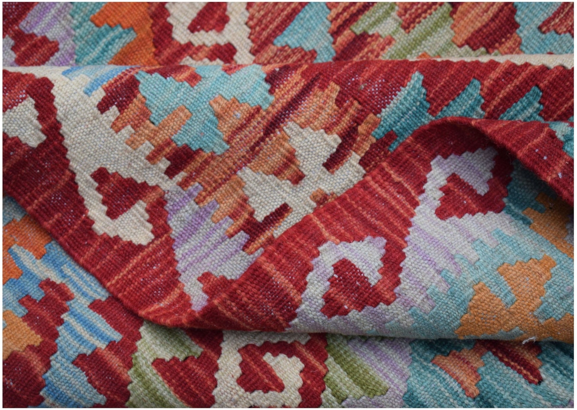 A handwoven Afghan Maimana kilim rug featuring a vibrant geometric pattern in wool.