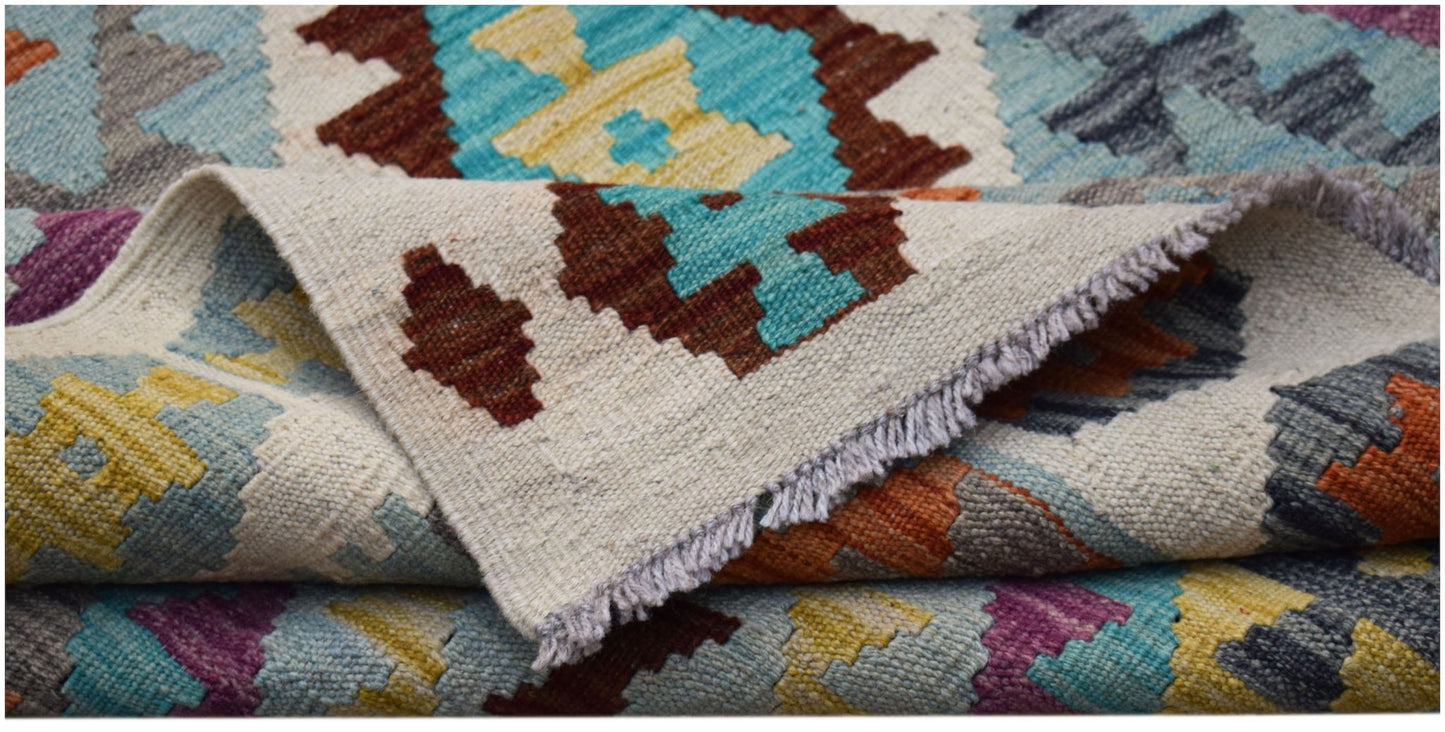 A handwoven Afghan Maimana kilim rug featuring a colorful geometric pattern on a cream background.