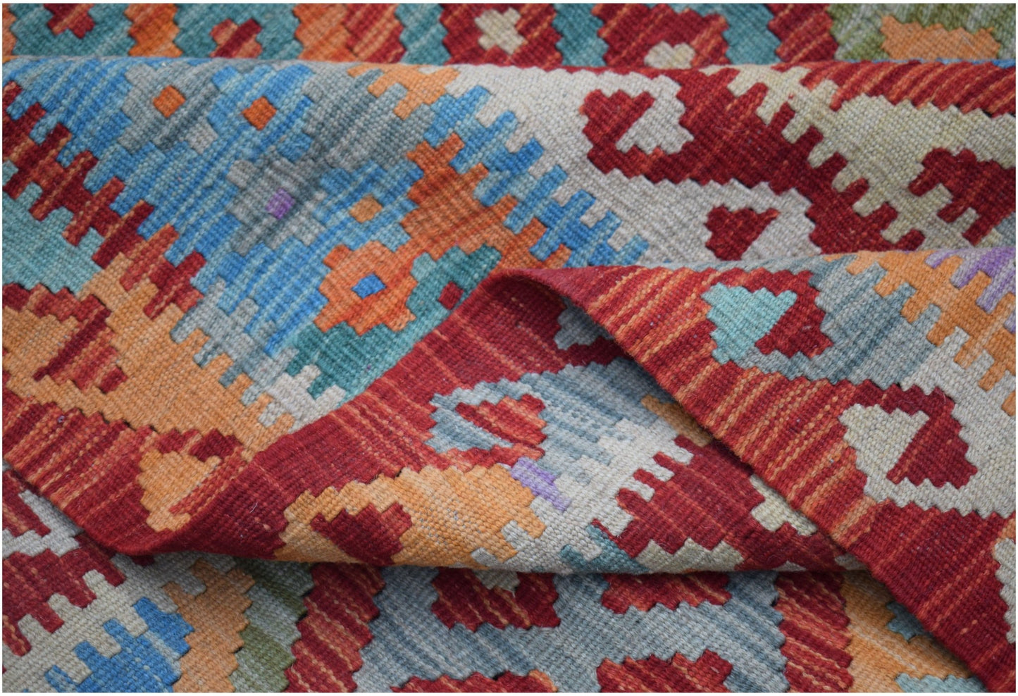 A handwoven Afghan Maimana kilim rug featuring a vibrant geometric pattern in wool.