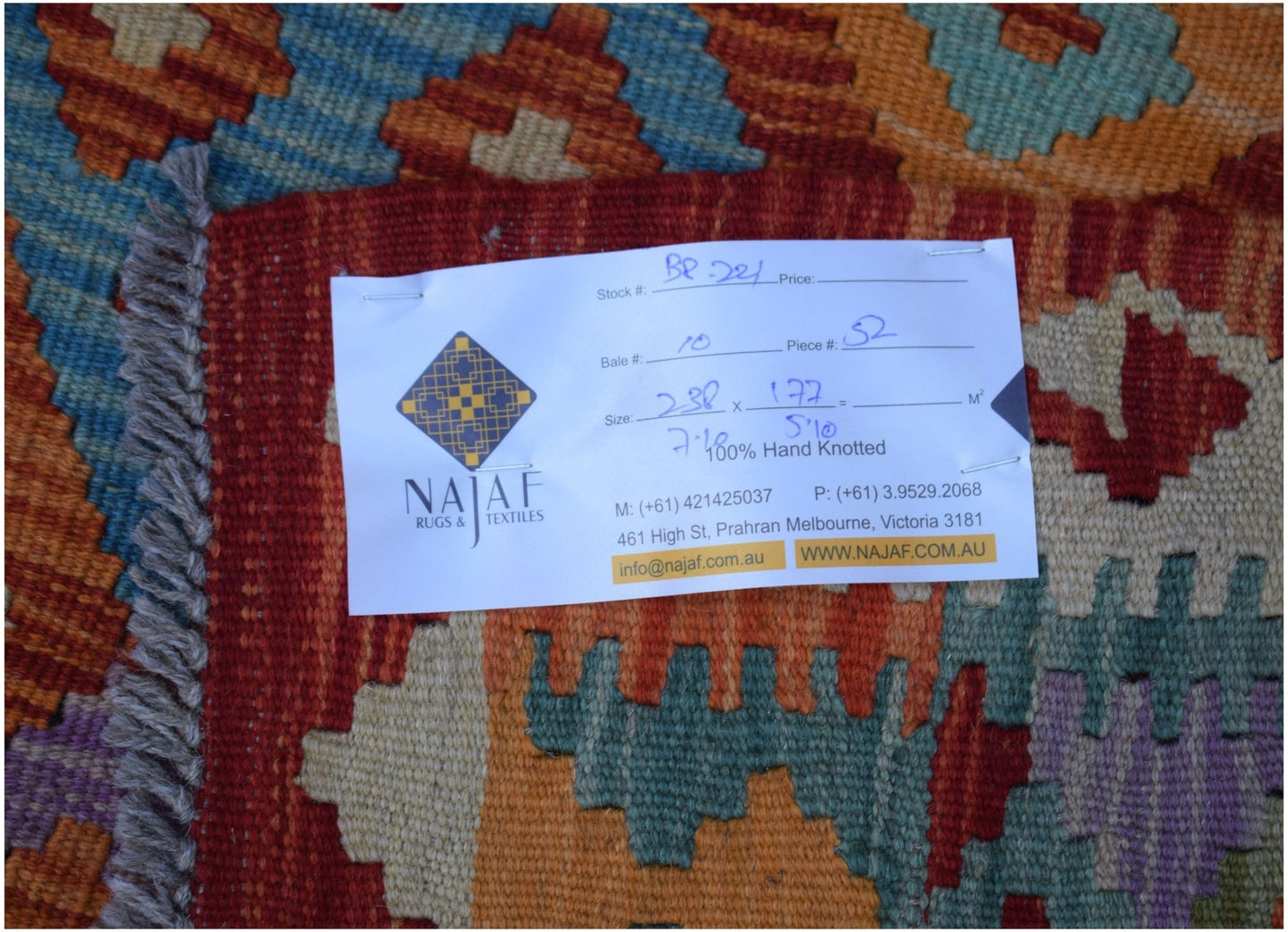 An Afghan Maimana Kilim rug featuring a geometric pattern in vibrant orange, blue, and purple.