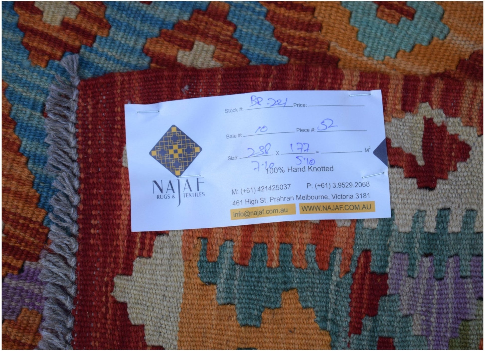 An Afghan Maimana Kilim rug featuring a geometric pattern in vibrant orange, blue, and purple.