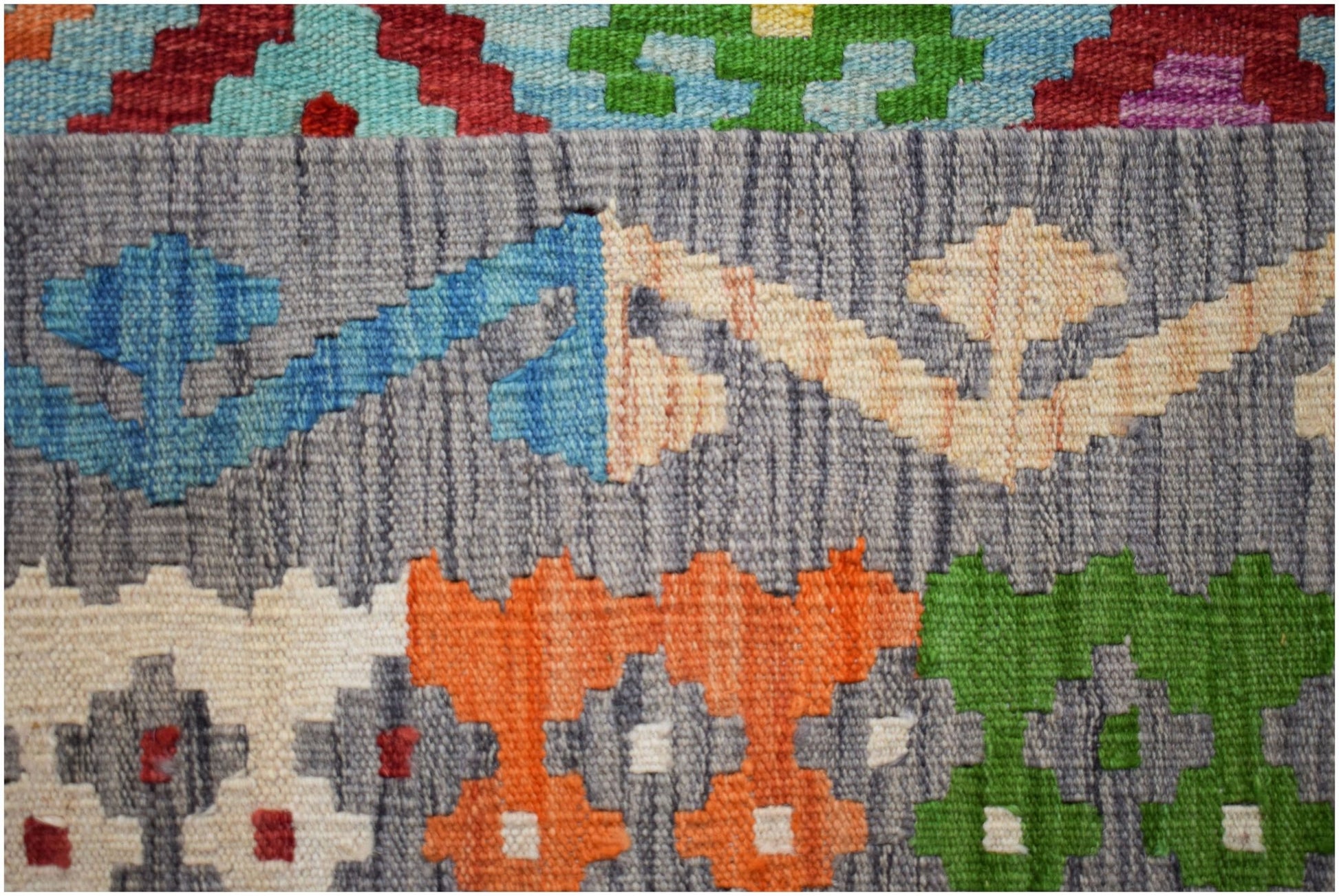 A handmade Afghan Maimana kilim featuring a flatweave texture with colorful geometric patterns.