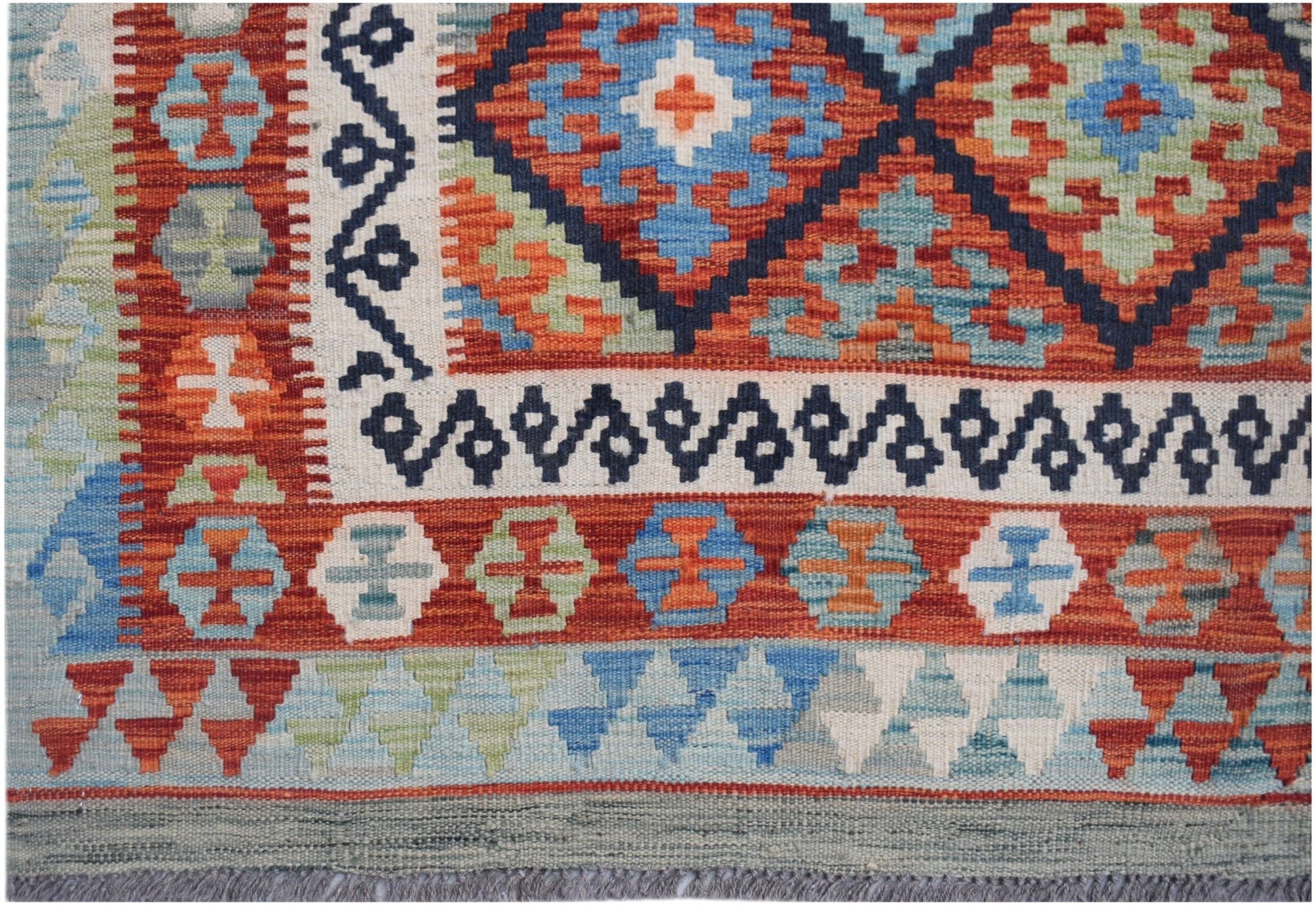 Handwoven Afghan Maimana kilim rug featuring a geometric pattern in vibrant red, blue, and green.