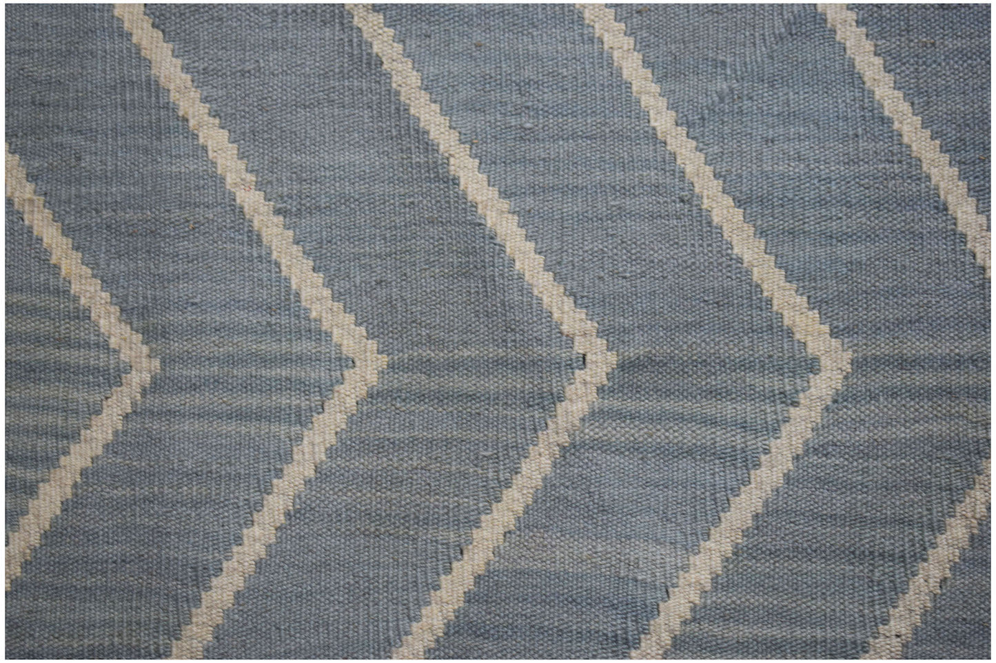 A handwoven wool Afghan Maimana kilim featuring a blue and cream geometric chevron pattern.