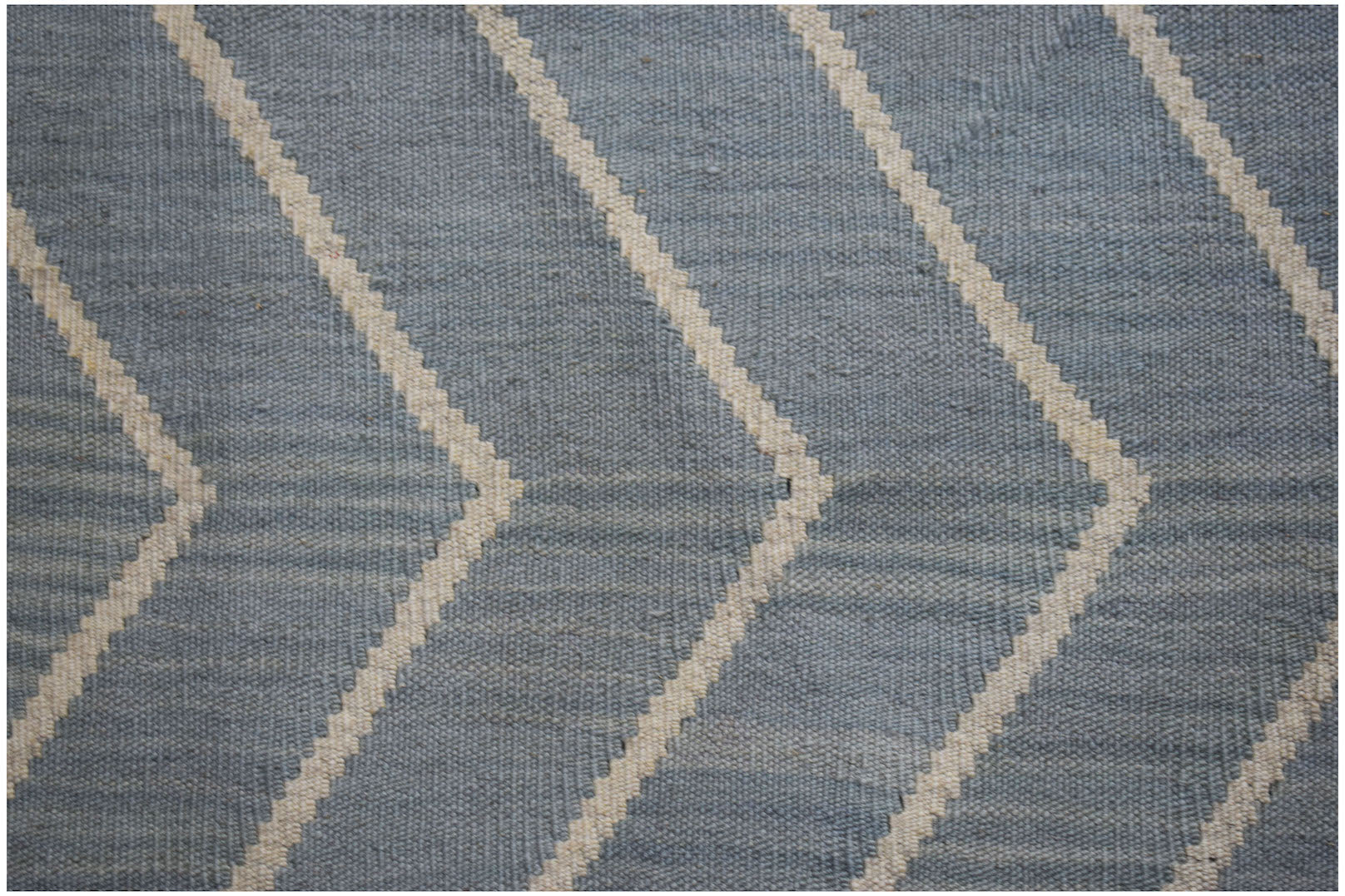 A handwoven wool Afghan Maimana kilim featuring a blue and cream geometric chevron pattern.