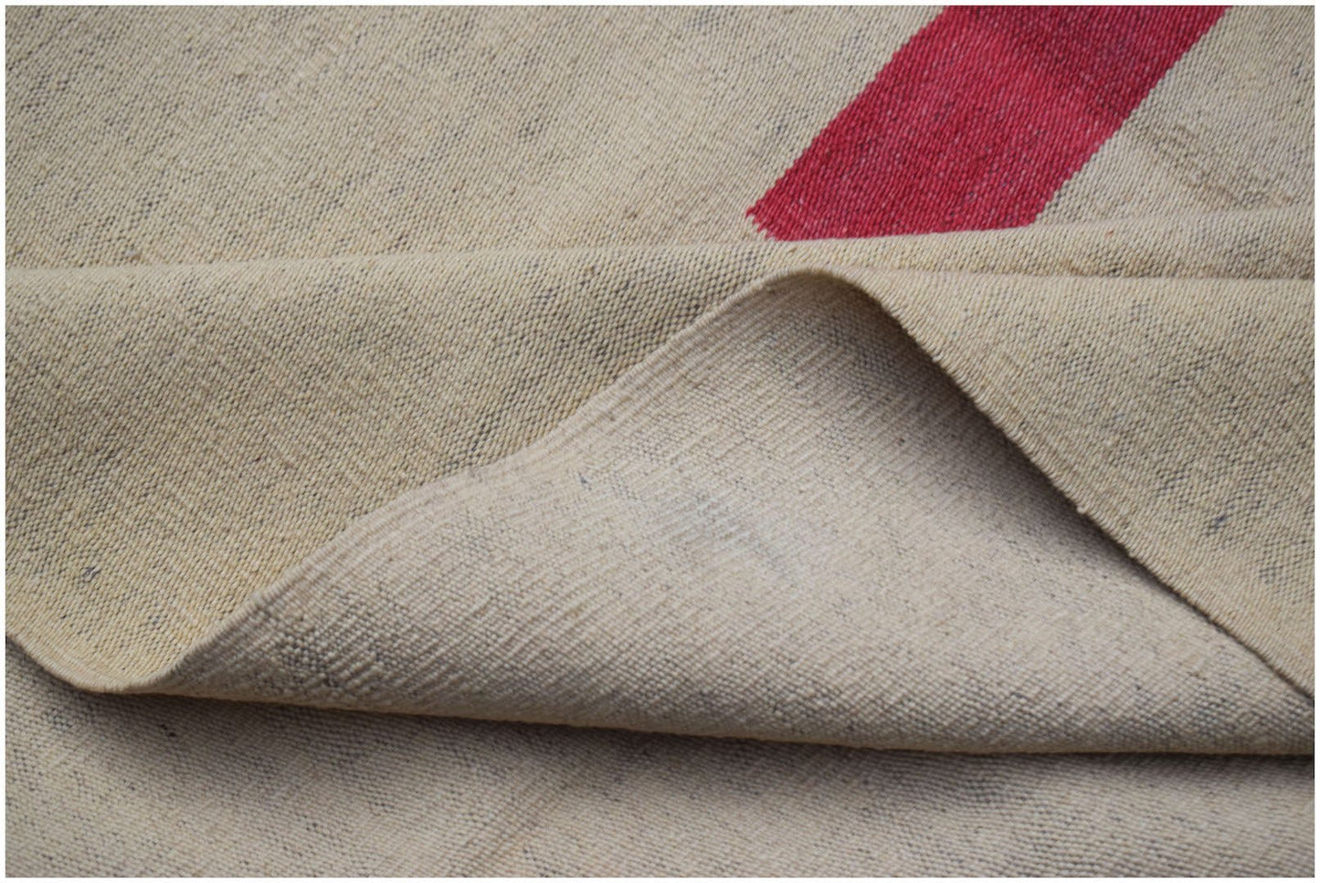 A handwoven Afghan Maimana kilim rug with a flatweave texture and a red geometric stripe.