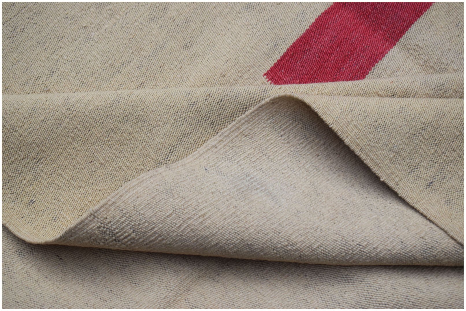 A handwoven Afghan Maimana kilim rug with a flatweave texture and a red geometric stripe.