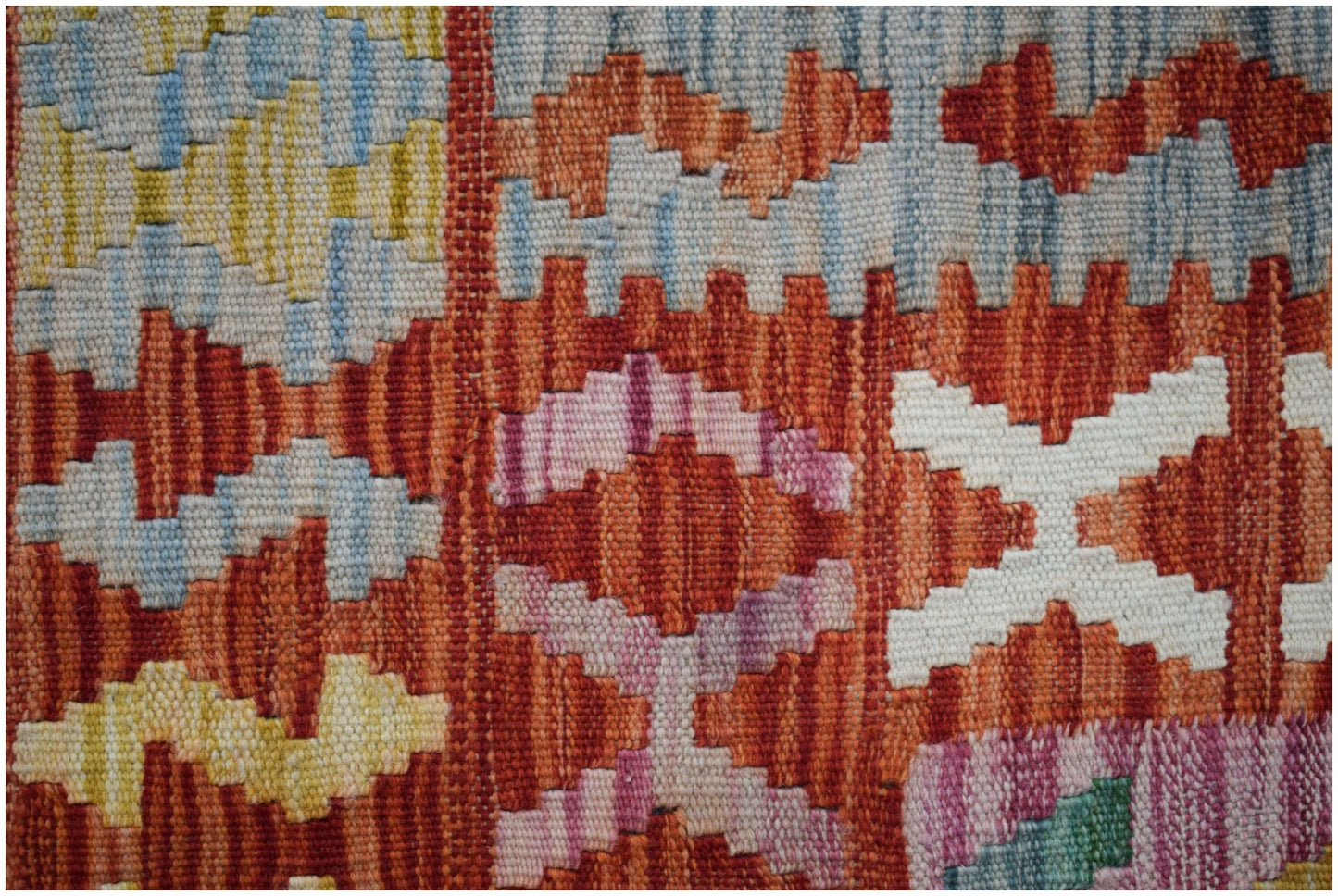 A close-up of a handmade Afghan Maimana kilim featuring geometric patterns in vibrant colors.