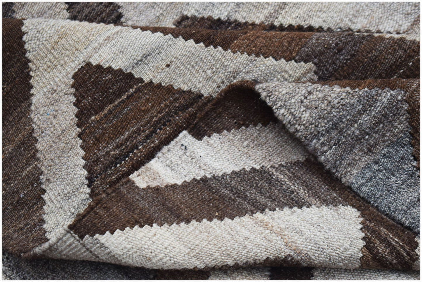 A handwoven Afghan Maimana kilim featuring a geometric pattern in shades of brown and cream.
