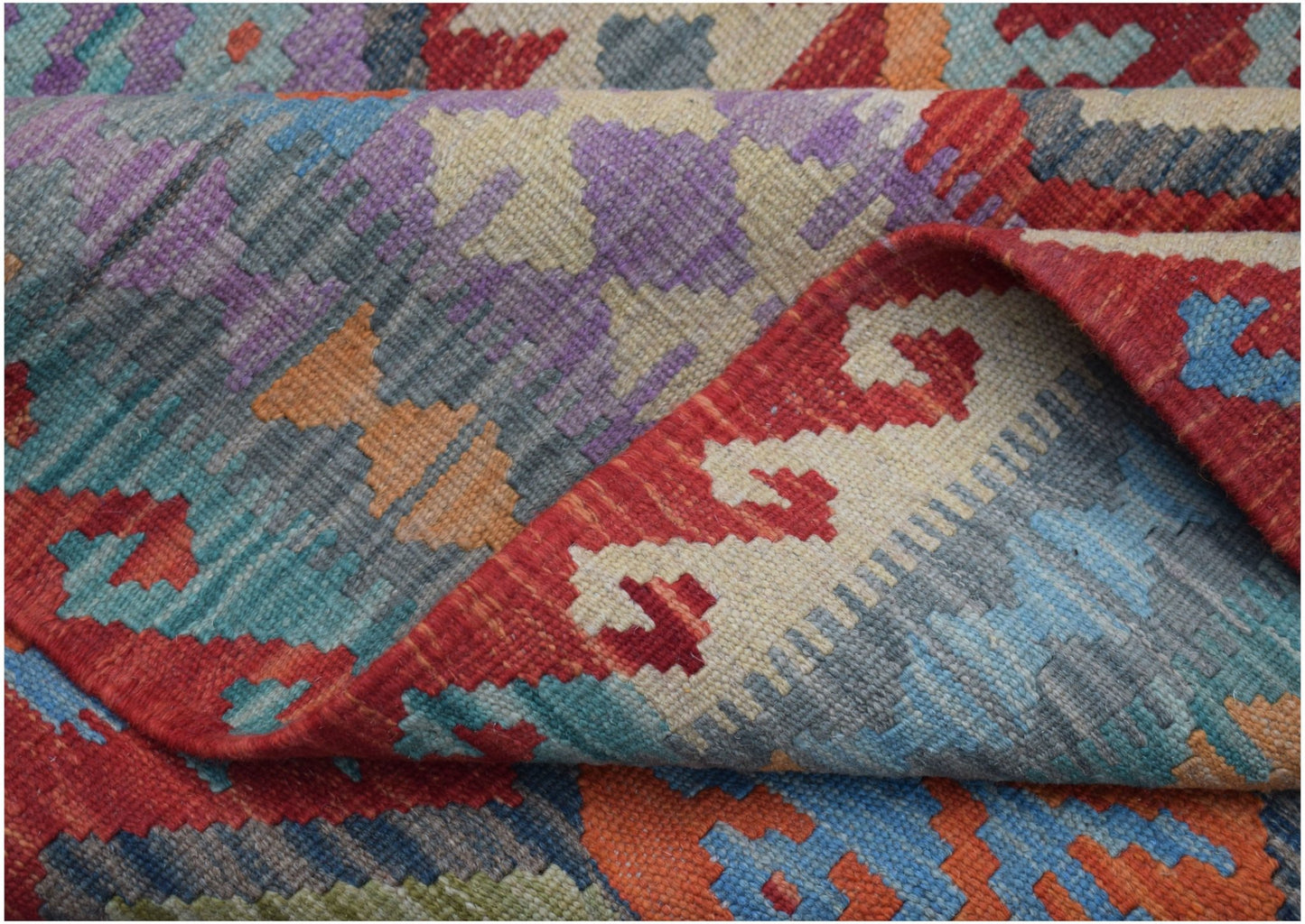 A handmade Afghan Maimana kilim rug featuring a vibrant geometric pattern in wool.
