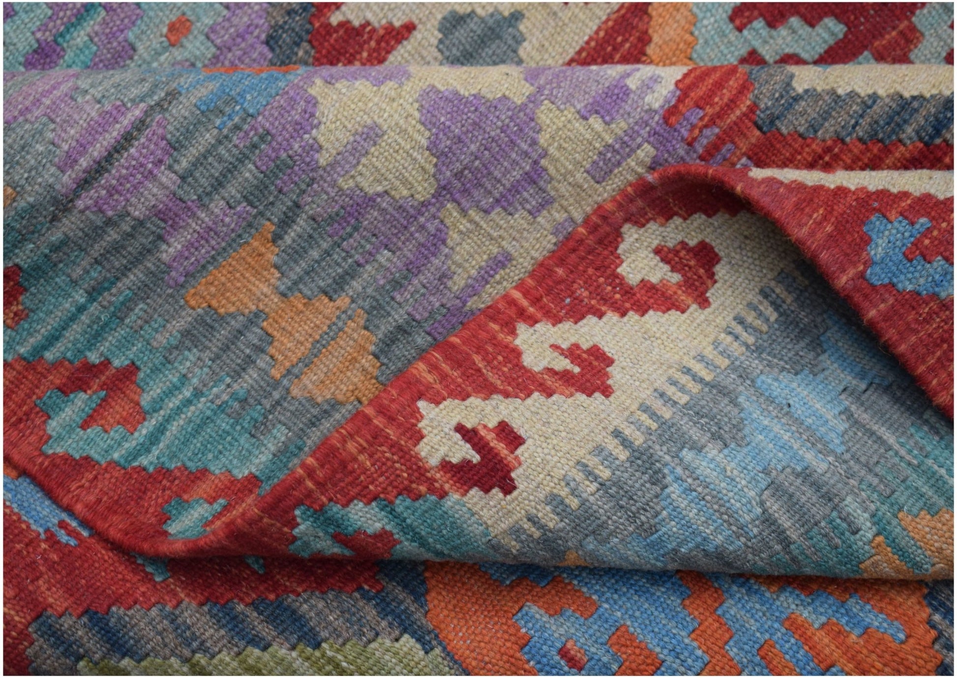 A handmade Afghan Maimana kilim rug featuring a vibrant geometric pattern in wool.