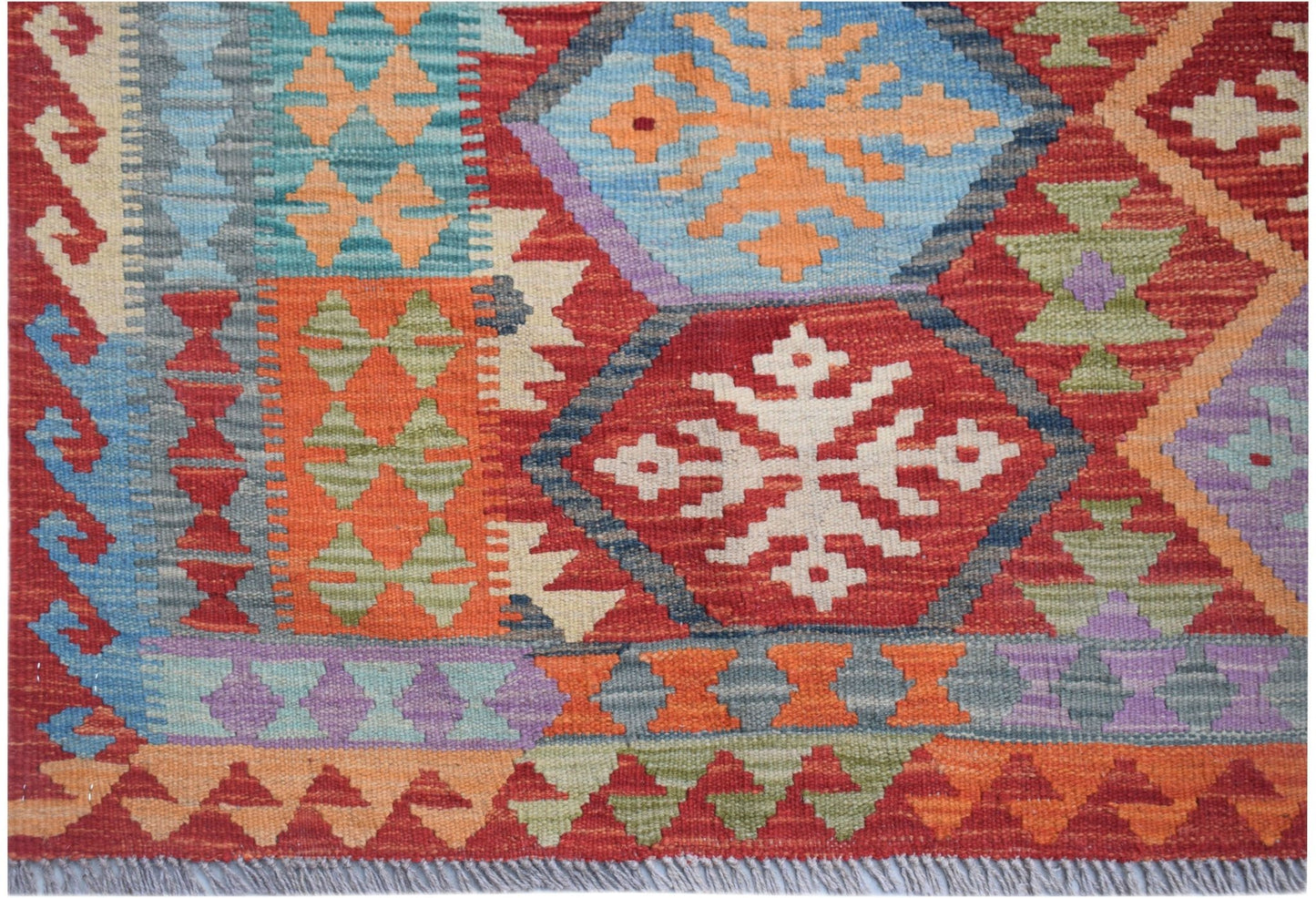 Handwoven Afghan Maimana kilim rug featuring a vibrant geometric pattern in wool.