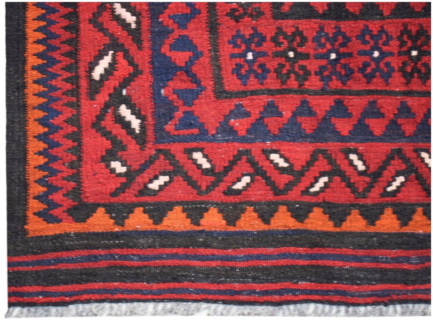 A handmade Afghan Maimana kilim featuring geometric patterns in red, blue, black, and orange.