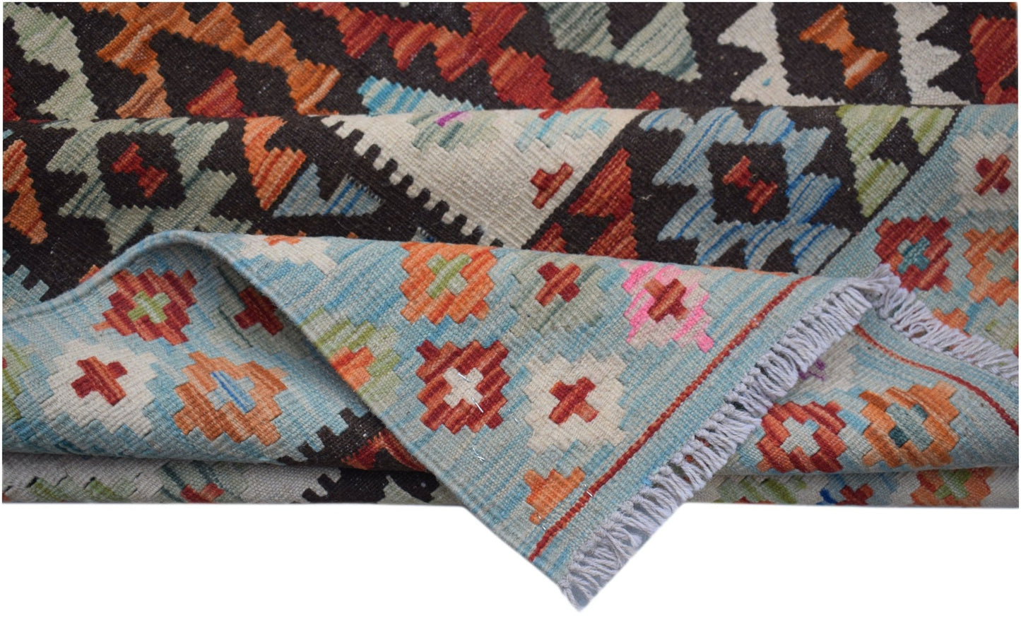 A handmade Afghan Maimana kilim rug featuring geometric patterns in vibrant red, blue, and orange.