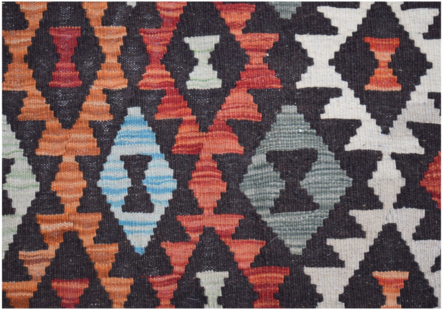 Handwoven Afghan Maimana kilim featuring a geometric diamond pattern in vibrant wool colors.