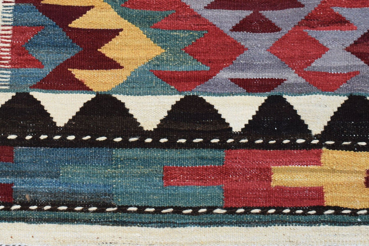 Handwoven Afghan Maimana kilim rug featuring a geometric pattern in red, blue, yellow, and black.