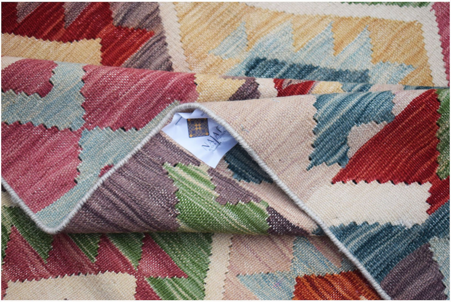 A handwoven Afghan Maimana kilim rug featuring a colorful geometric pattern and flatweave texture.