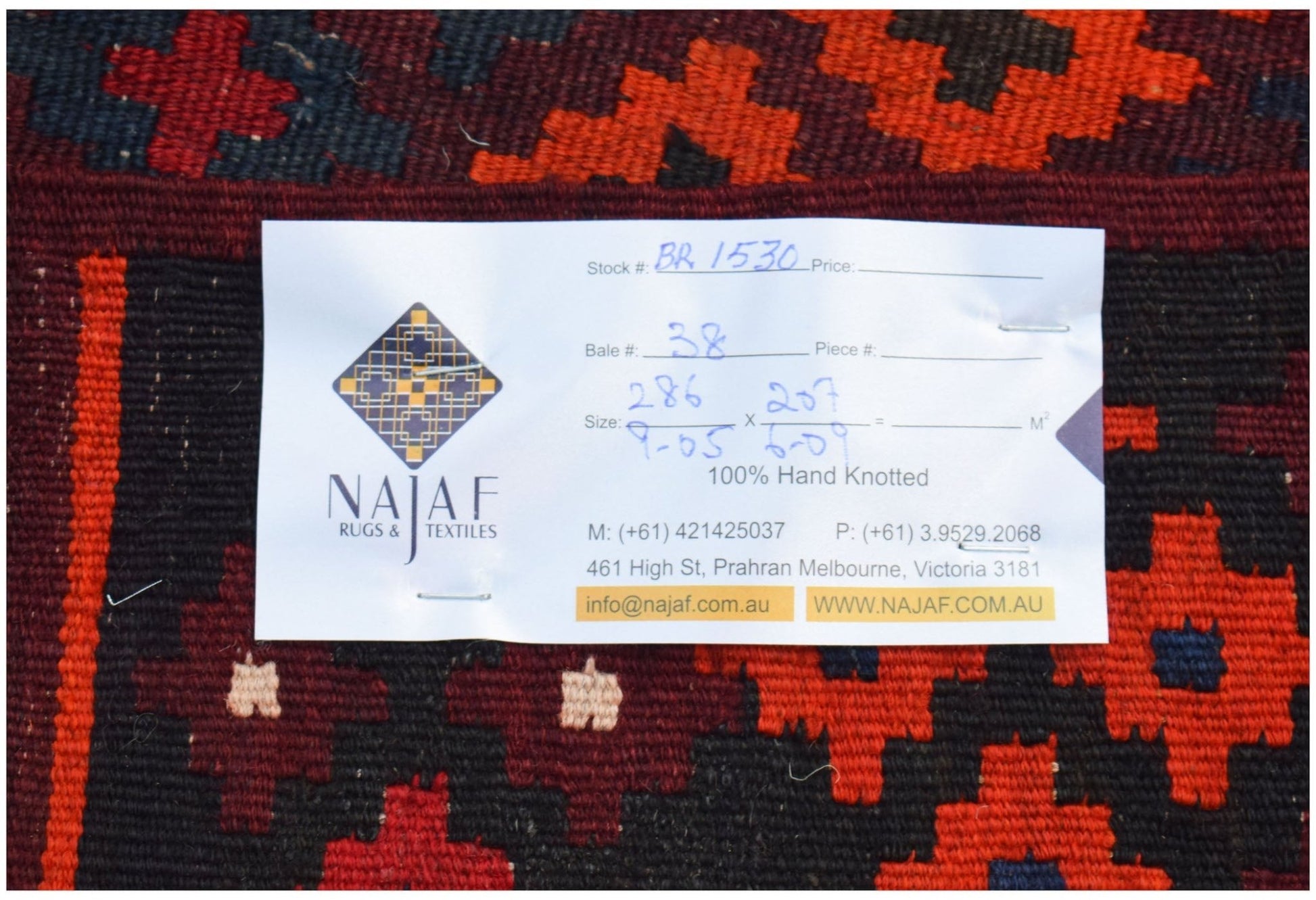 An Afghan Maimana Kilim rug featuring a geometric pattern in red, black, and dark blue.