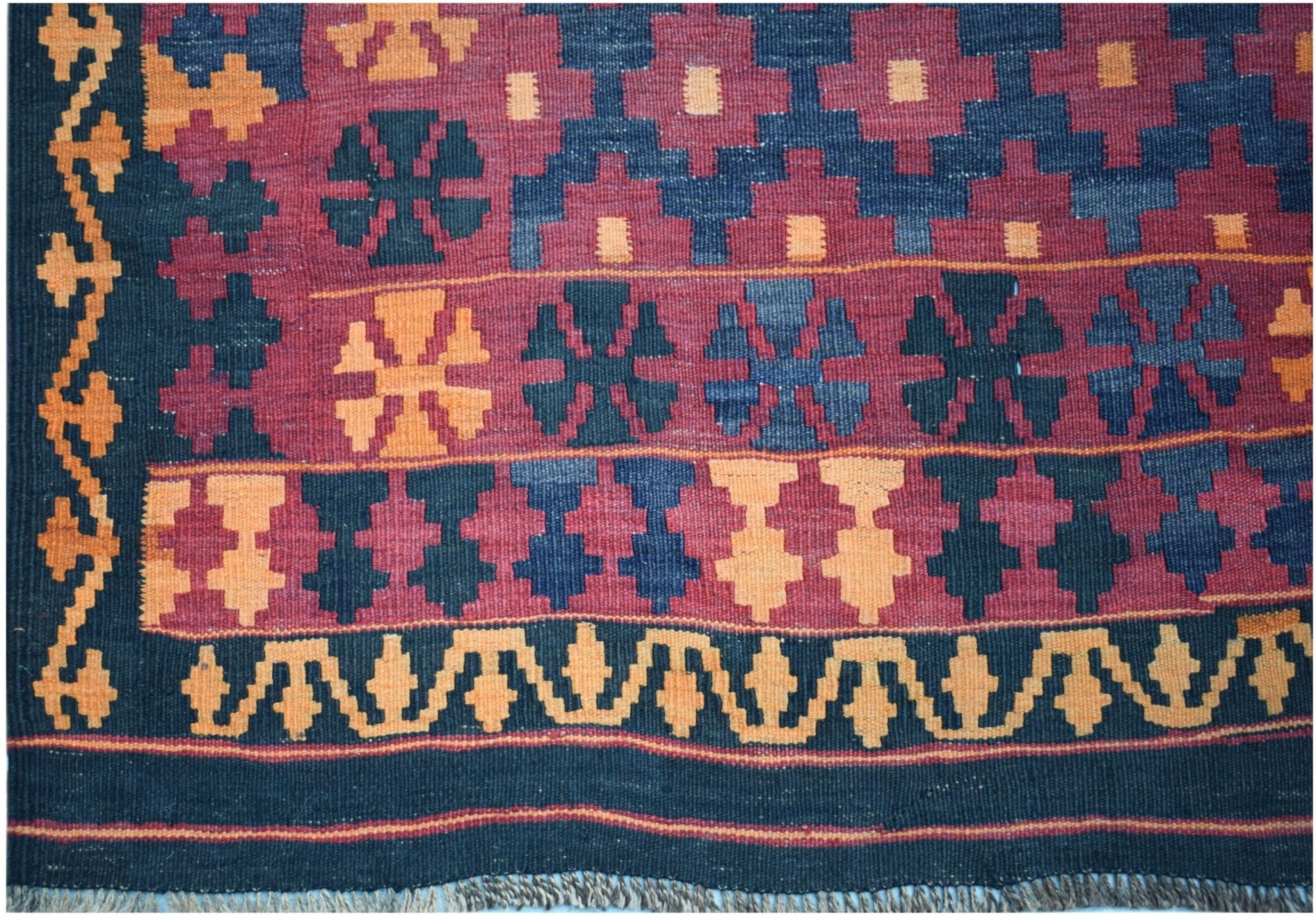 Handwoven Afghan Maimana kilim featuring geometric patterns in red, blue, and orange wool.