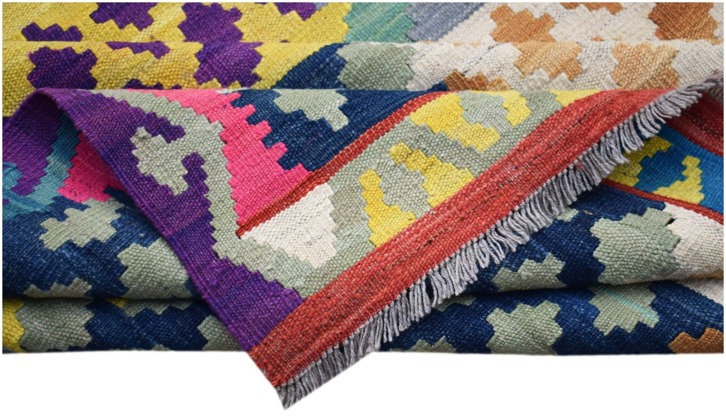 A handwoven Afghan Maimana kilim rug featuring a vibrant geometric pattern and fringed edges.