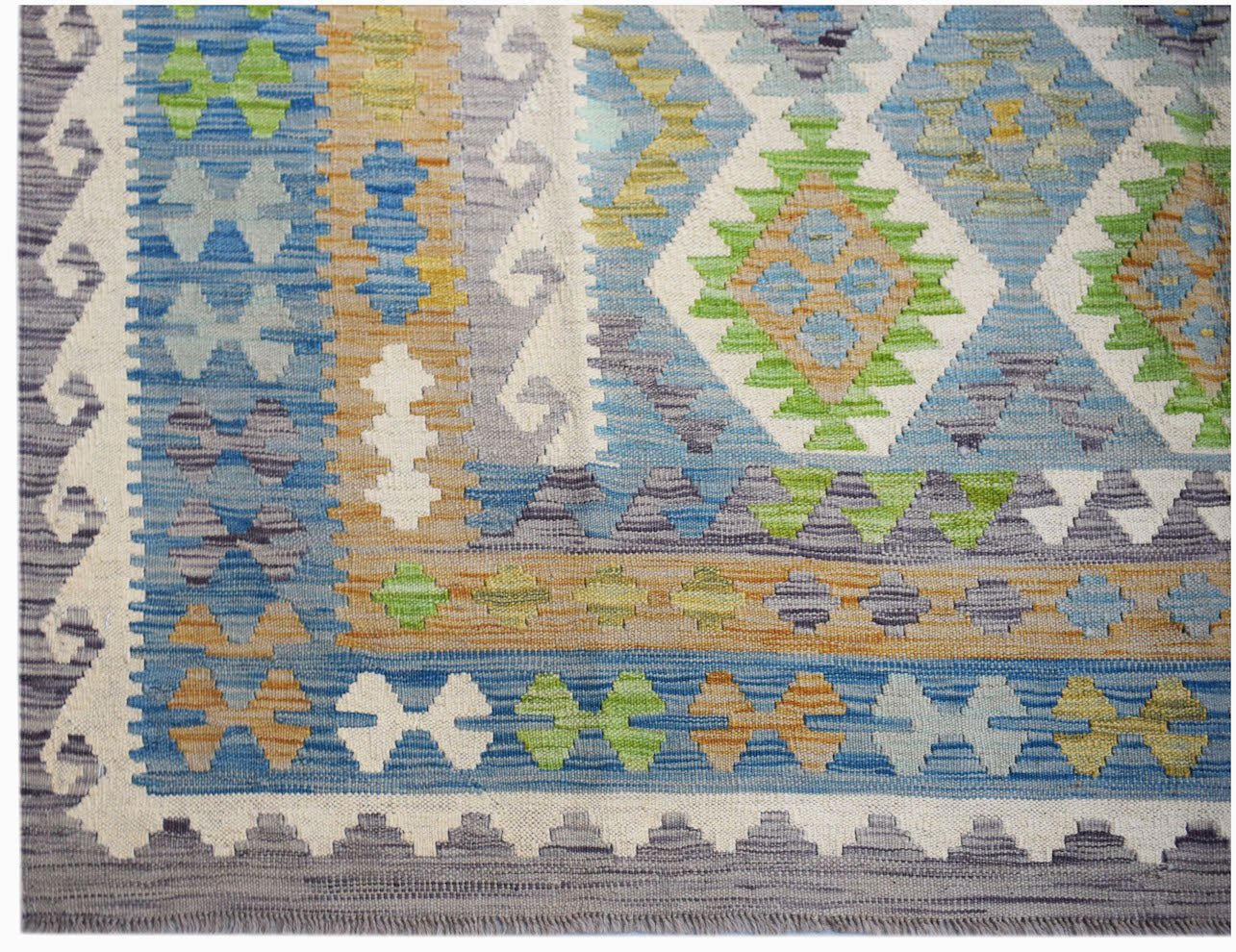 A handmade Afghan Maimana kilim rug featuring a geometric pattern in blue, green, and tan tones.