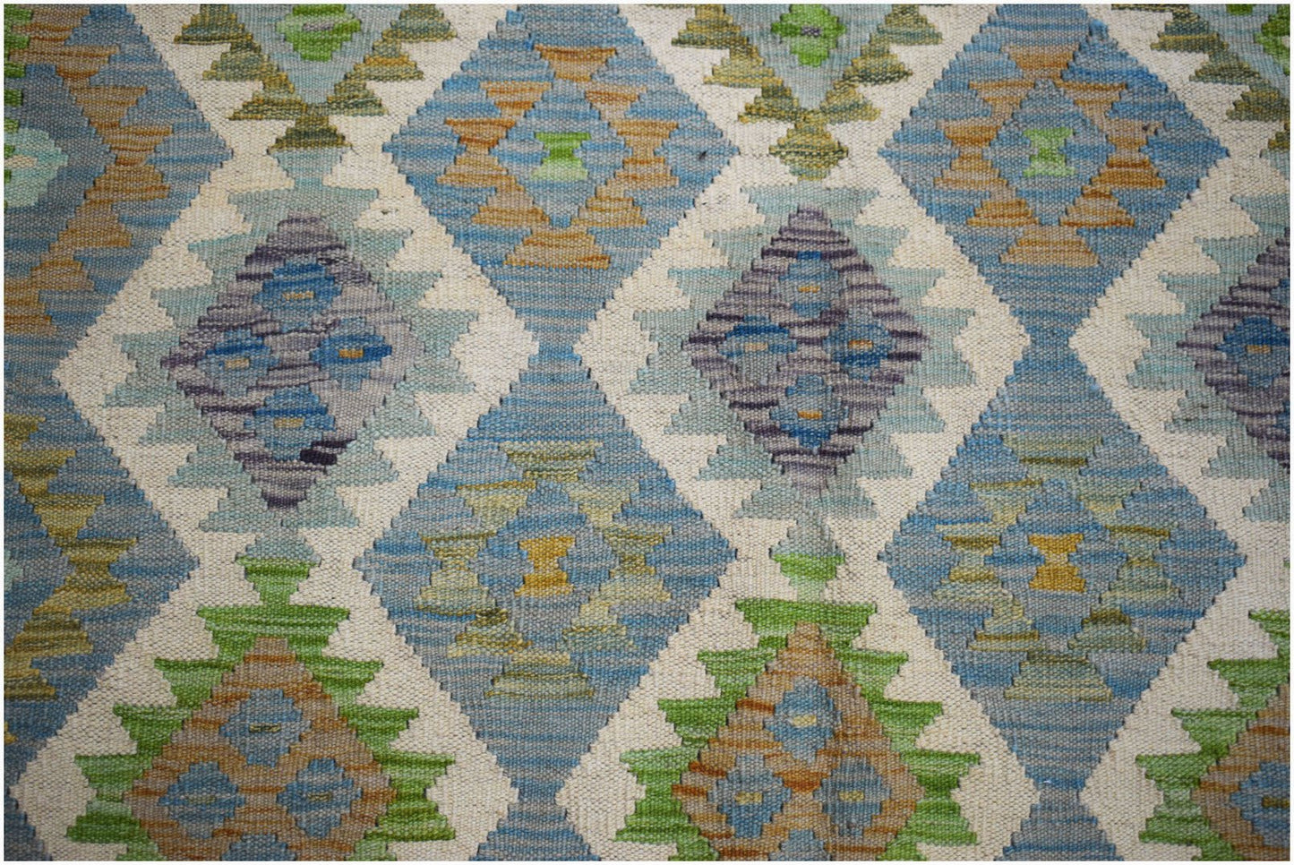 Handwoven Afghan Maimana kilim featuring a repeating diamond pattern in blue, green, and tan wool.