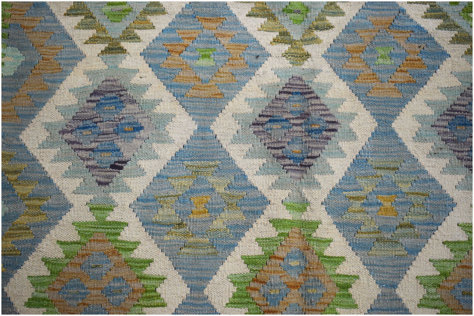 Handwoven Afghan Maimana kilim featuring a repeating diamond pattern in blue, green, and tan wool.