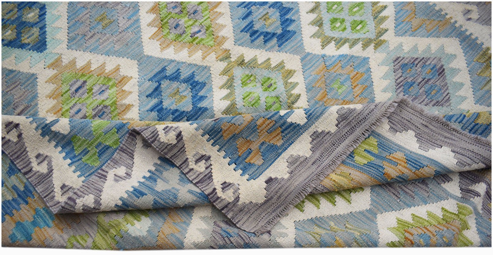 A handmade Afghan Maimana kilim rug featuring a geometric pattern in blue, green, and tan wool.