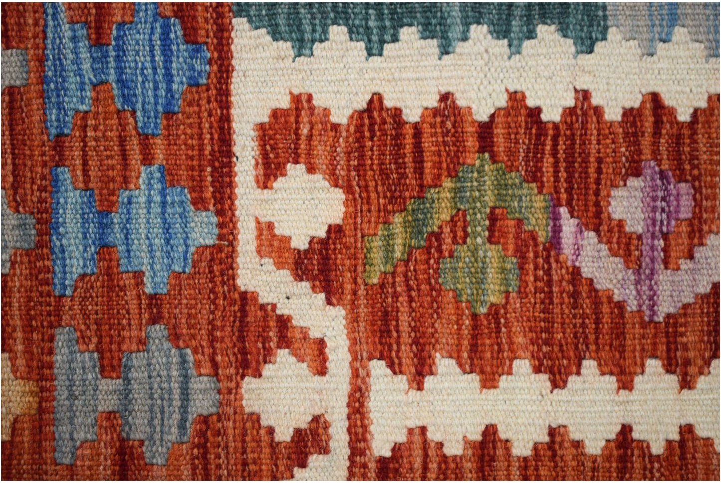 A close-up of a handmade Afghan Maimana kilim featuring geometric patterns in wool.