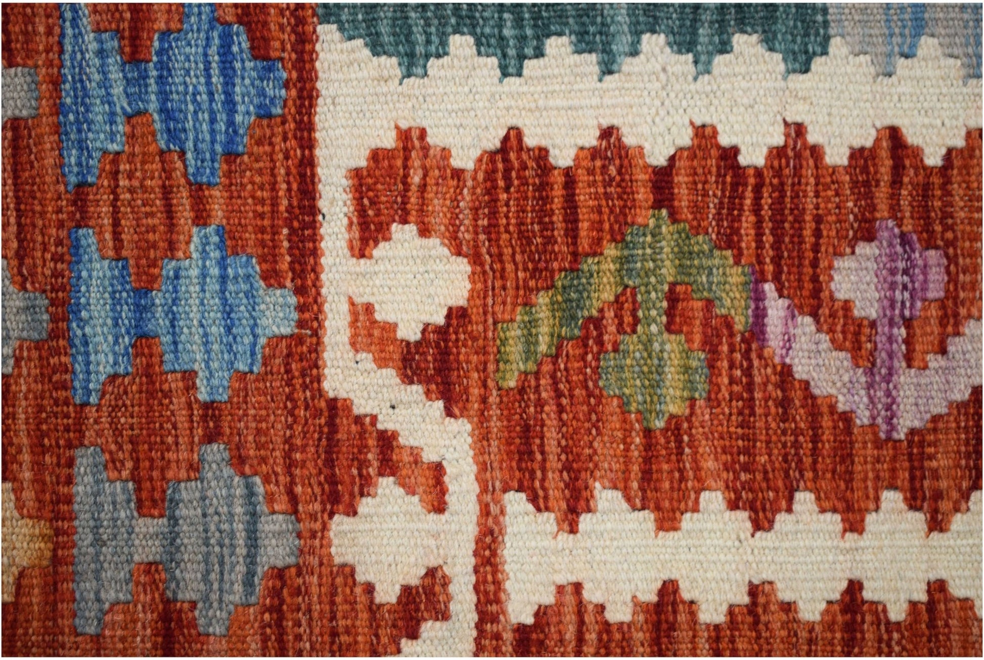 A close-up of a handmade Afghan Maimana kilim featuring geometric patterns in wool.