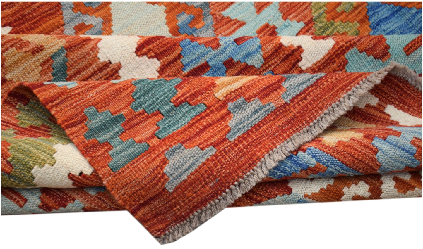 A handwoven Afghan Maimana kilim rug featuring a geometric pattern in vibrant, multi-colored wool.