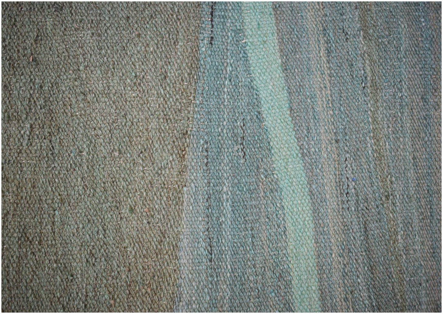 A close-up of a handmade Afghan Maimana wool kilim featuring a flat-weave texture in green tones.
