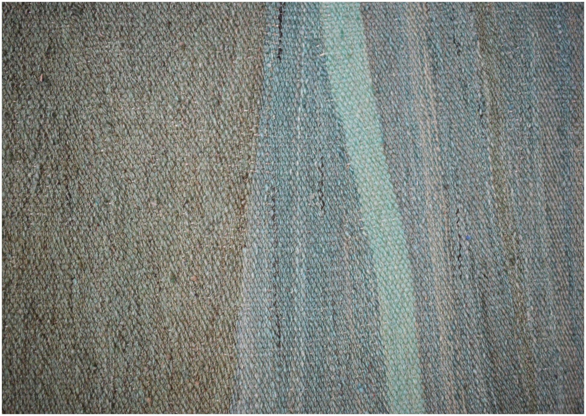 A close-up of a handmade Afghan Maimana wool kilim featuring a flat-weave texture in green tones.