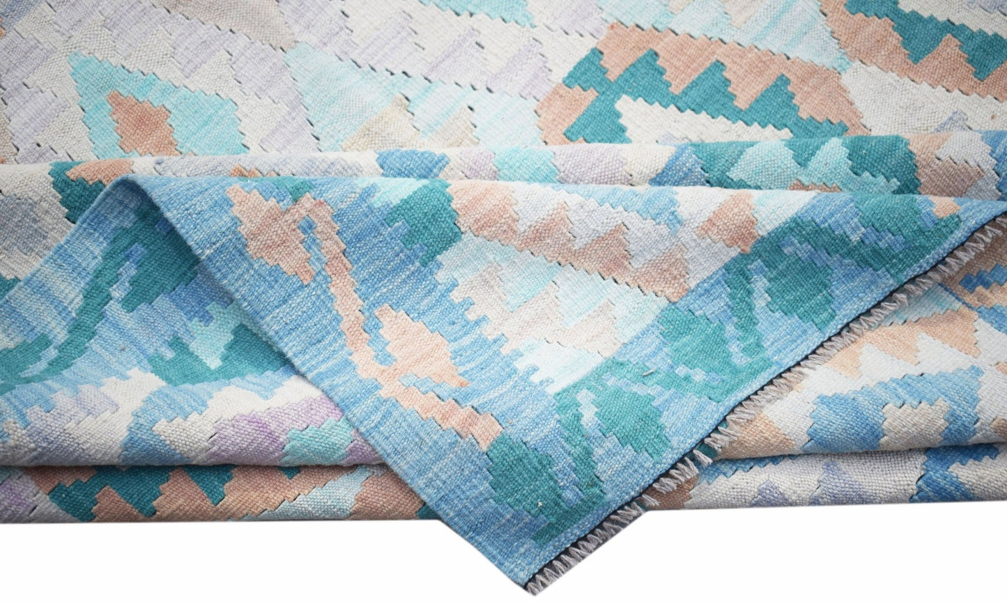 A handmade Afghan Maimana kilim rug featuring a geometric pattern in blue, teal, and peach tones.
