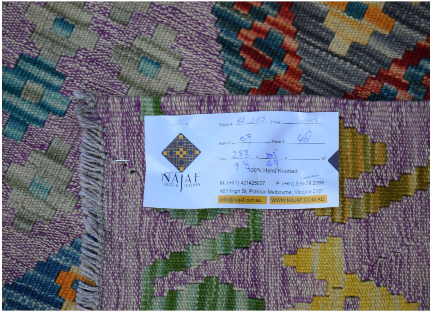 A handwoven Afghan Maimana kilim featuring a vibrant geometric pattern in purple, orange, and blue.